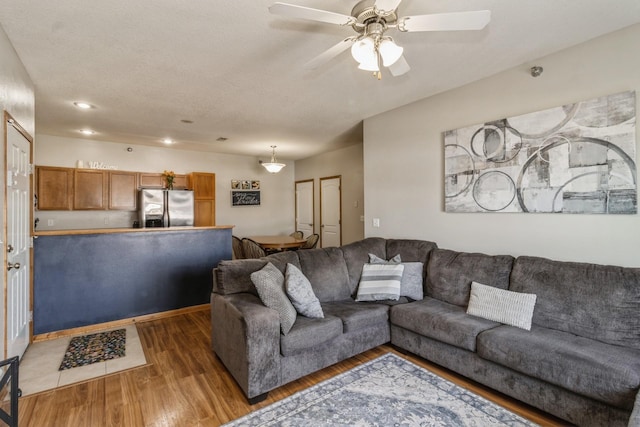 living area featuring dark wood-type flooring, a textured ceiling, and a ceiling fan