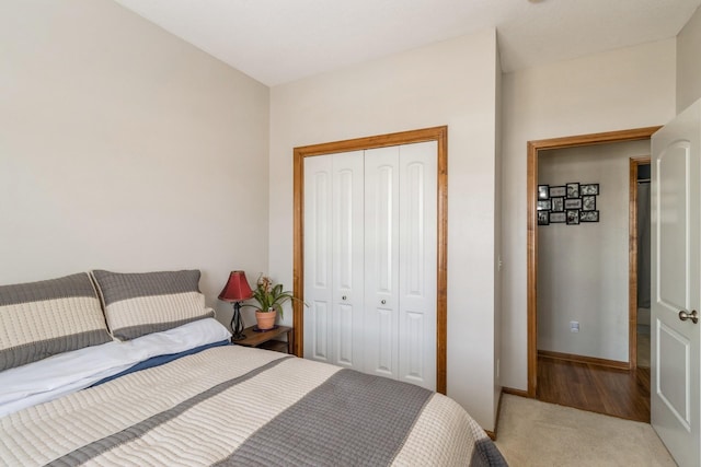 bedroom with baseboards, a closet, and light colored carpet