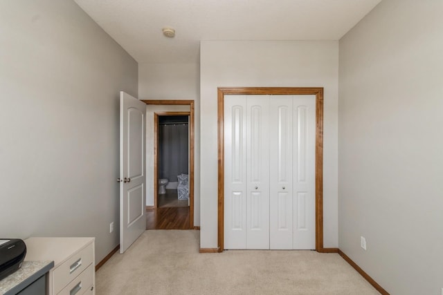 bedroom featuring baseboards, a closet, and light colored carpet