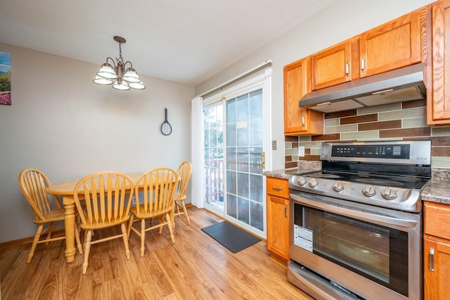 kitchen featuring brown cabinets, stainless steel electric range, light wood-type flooring, under cabinet range hood, and backsplash