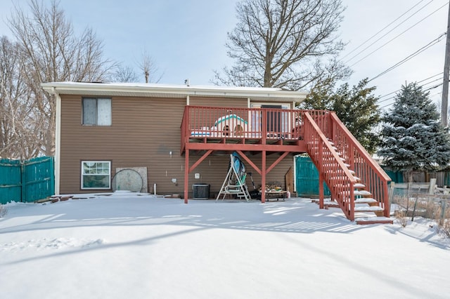 snow covered house featuring stairway, fence, and a wooden deck