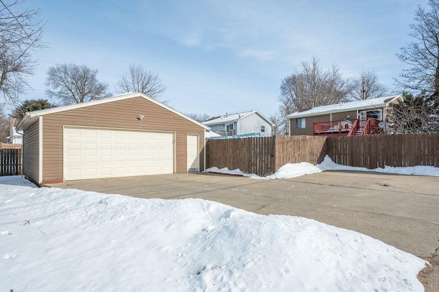 snow covered garage with a garage and fence