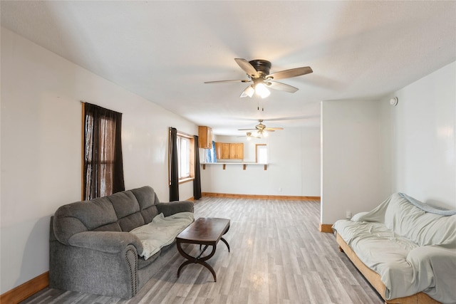 living room featuring light wood finished floors, ceiling fan, and baseboards