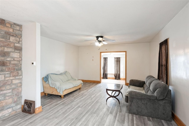 living area with light wood-style floors, ceiling fan, and baseboards