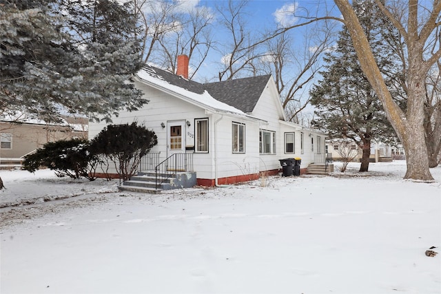 view of front of home with a shingled roof and a chimney