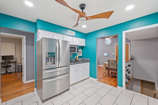 kitchen with stainless steel appliances, dark countertops, visible vents, a ceiling fan, and white cabinetry