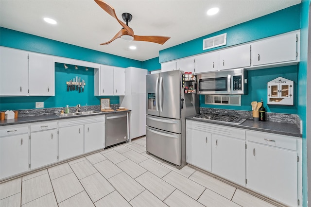 kitchen featuring appliances with stainless steel finishes, dark countertops, visible vents, and a sink