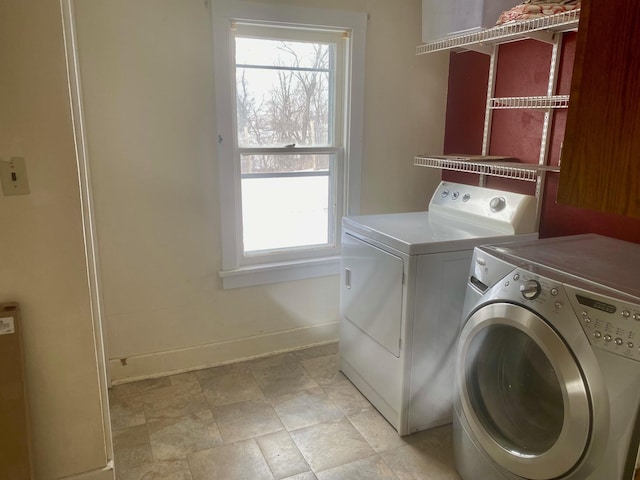 clothes washing area with laundry area, baseboards, separate washer and dryer, and a wealth of natural light