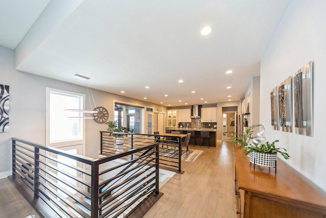 hall with recessed lighting, visible vents, baseboards, an upstairs landing, and light wood finished floors