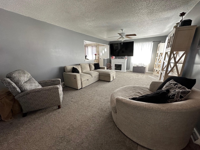 carpeted living area featuring a textured ceiling, a fireplace, and a ceiling fan