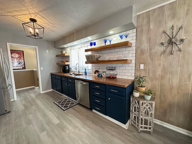 bar featuring a textured ceiling, appliances with stainless steel finishes, light wood-type flooring, and a sink