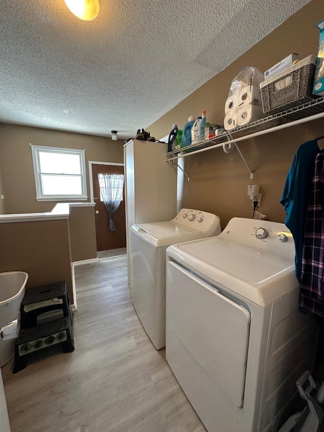 laundry room featuring light wood finished floors, laundry area, separate washer and dryer, and a textured ceiling