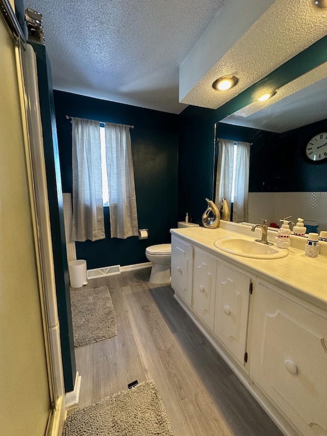 full bathroom featuring visible vents, toilet, a textured ceiling, vanity, and wood finished floors