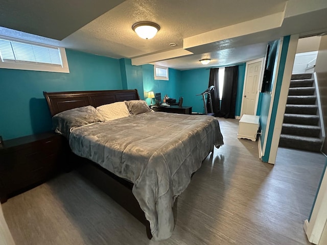 bedroom featuring a textured ceiling, baseboards, and wood finished floors