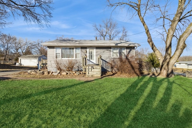 view of front of home with a garage, a front lawn, and an outbuilding