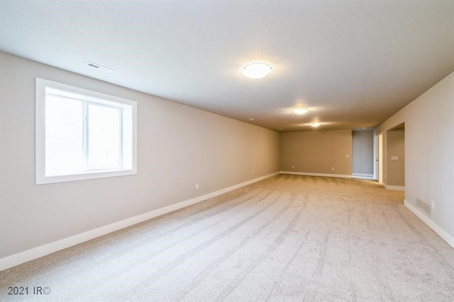 empty room featuring baseboards, visible vents, a textured ceiling, and light colored carpet