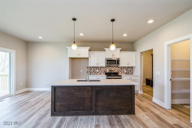 kitchen featuring white cabinets, decorative backsplash, appliances with stainless steel finishes, light countertops, and a sink