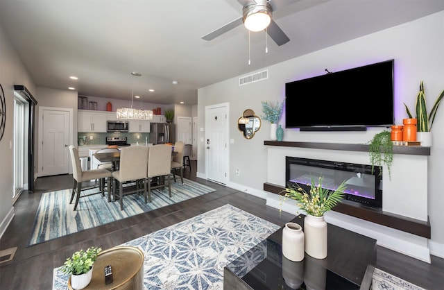 living area with dark wood-type flooring, recessed lighting, visible vents, and baseboards