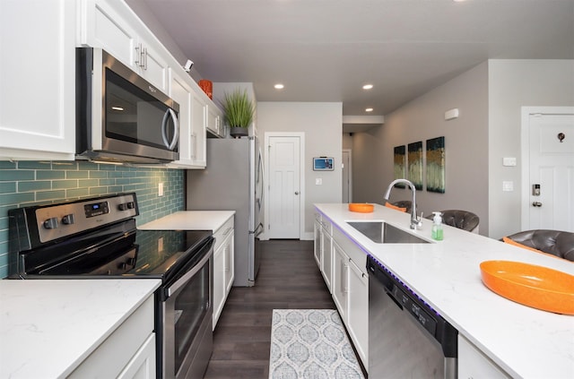 kitchen with stainless steel appliances, white cabinetry, a sink, and light stone countertops