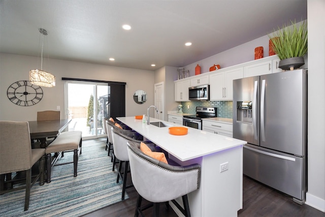 kitchen featuring white cabinets, an island with sink, appliances with stainless steel finishes, light countertops, and a sink