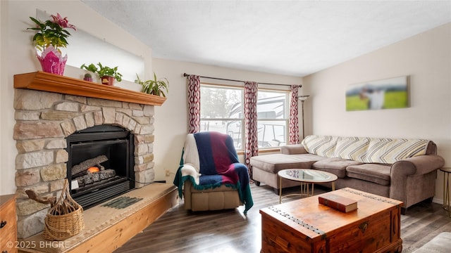 living area with a stone fireplace, vaulted ceiling, and wood finished floors