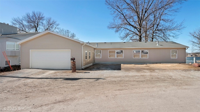 back of house with an attached garage and dirt driveway