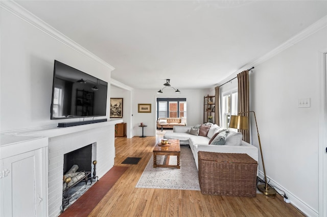 living area with crown molding, a fireplace, baseboards, and wood finished floors