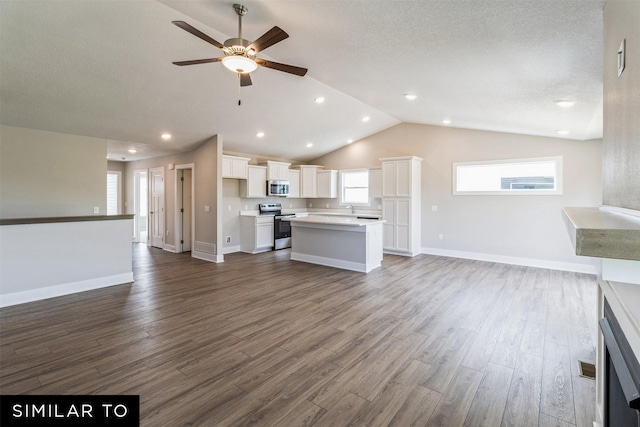 unfurnished living room with dark wood-style floors, lofted ceiling, a ceiling fan, and baseboards