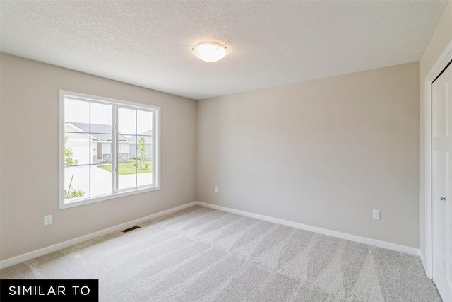 unfurnished room featuring light carpet, a textured ceiling, visible vents, and baseboards