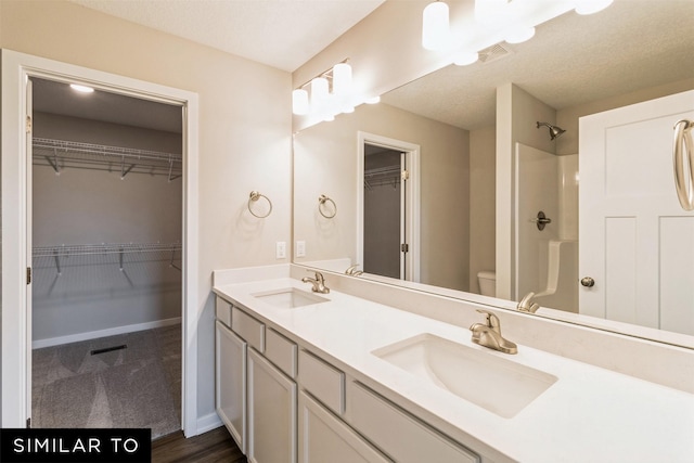 full bath featuring a shower, a sink, toilet, and double vanity