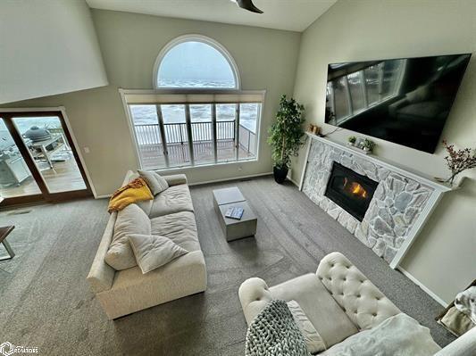 carpeted living room with ceiling fan, a fireplace, baseboards, and vaulted ceiling