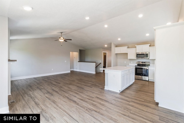 kitchen featuring white cabinets, open floor plan, a center island, stainless steel appliances, and light countertops