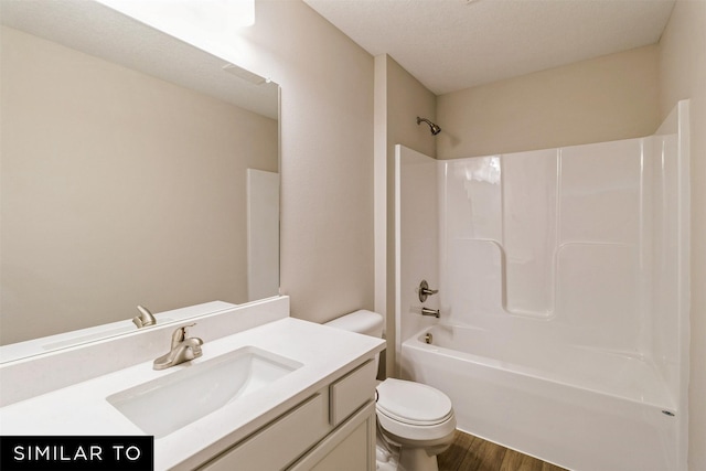 bathroom featuring toilet, vanity, wood finished floors, and shower / bathtub combination