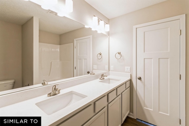 full bath with visible vents, double vanity, a sink, and toilet