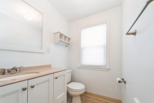 bathroom with toilet, vanity, and baseboards