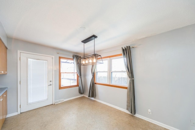 unfurnished dining area featuring a textured ceiling, visible vents, and baseboards