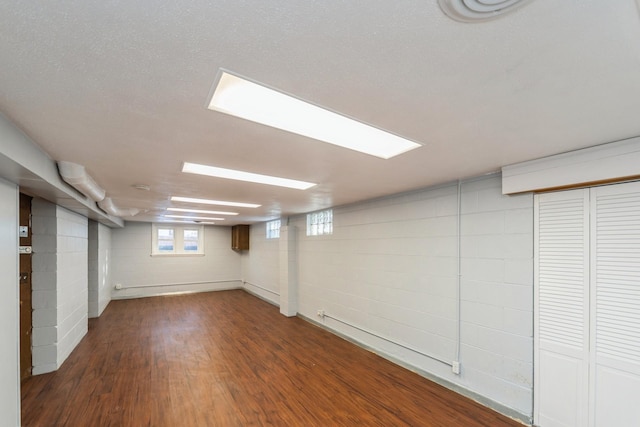 below grade area featuring concrete block wall and wood finished floors