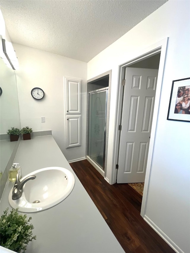 full bath featuring a textured ceiling, a stall shower, wood finished floors, and vanity