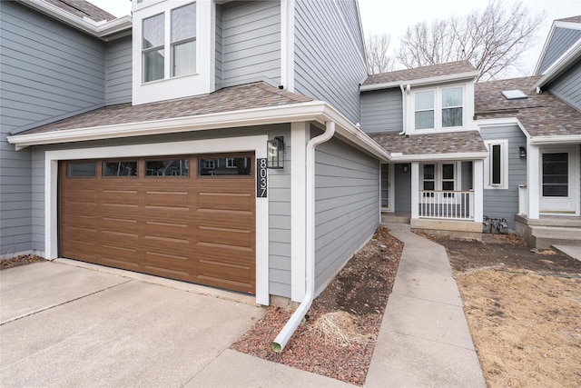 entrance to property with an attached garage and roof with shingles