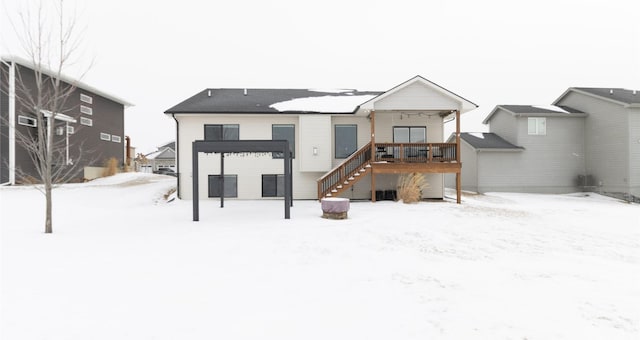 snow covered back of property featuring stairway and a wooden deck