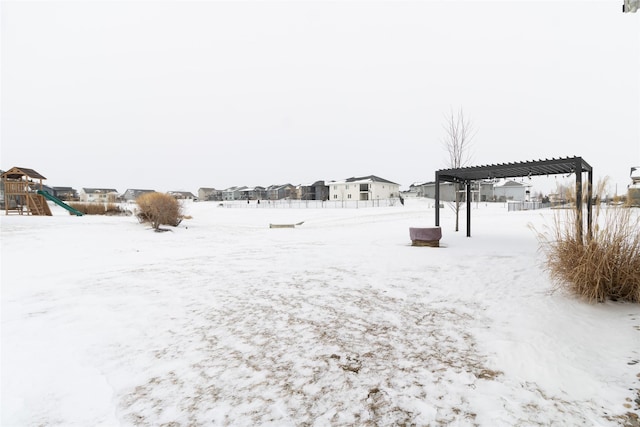 snowy yard featuring playground community and a pergola