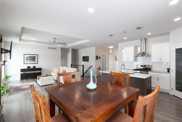 dining room featuring a tray ceiling, dark wood finished floors, recessed lighting, visible vents, and a ceiling fan