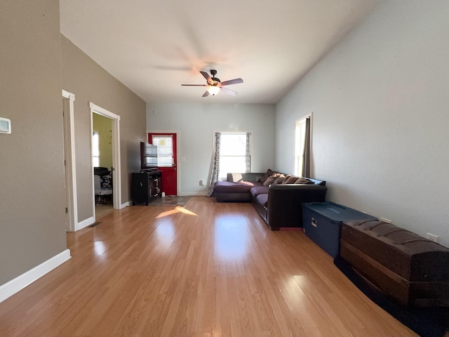 living area with a ceiling fan, baseboards, and wood finished floors