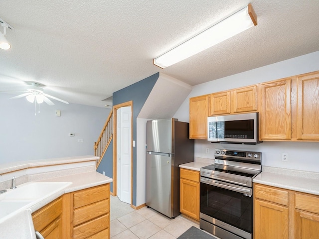 kitchen with stainless steel appliances, light countertops, a textured ceiling, and light tile patterned flooring