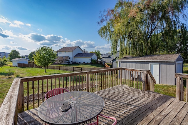 wooden terrace featuring a fenced backyard, an outdoor structure, a lawn, a shed, and outdoor dining space