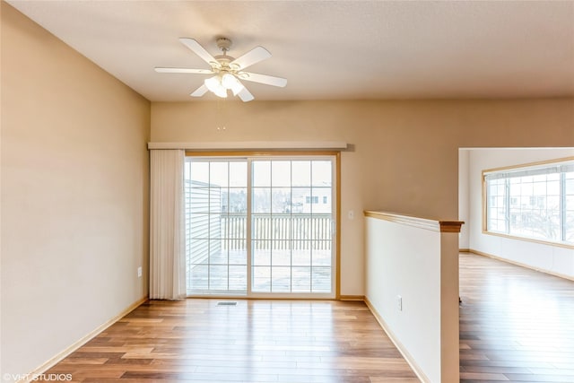 spare room featuring light wood-style floors, plenty of natural light, and ceiling fan