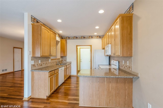 kitchen with white appliances, light brown cabinets, light stone counters, and a sink