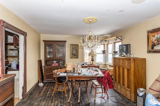 dining area featuring dark wood-style floors, a notable chandelier, and baseboards