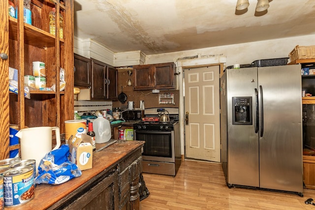 kitchen with stainless steel appliances, dark brown cabinets, dark countertops, and light wood-style floors