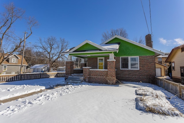 view of front of house with a garage, brick siding, fence, and a chimney